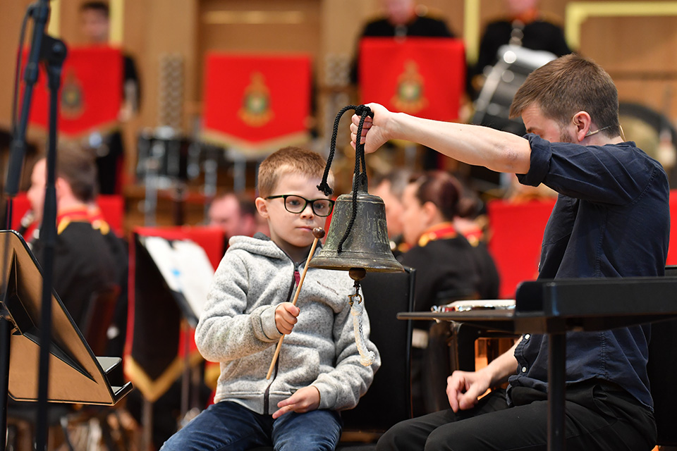A child hitting a bell with percussionist Owen Gunnell, in the RCM's Amaryllis Fleming Concert Hall